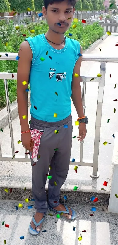 Young man in blue shirt standing outdoors by railing.