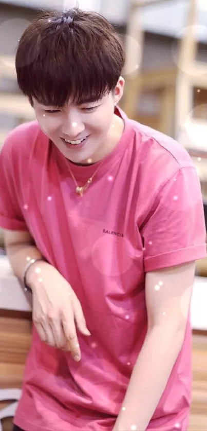 Mobile wallpaper of a young man in a pink shirt with a casual smile.