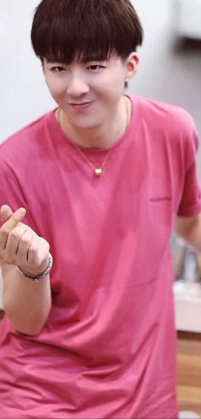 Person in a vibrant pink t-shirt making a hand gesture in a casual setting.