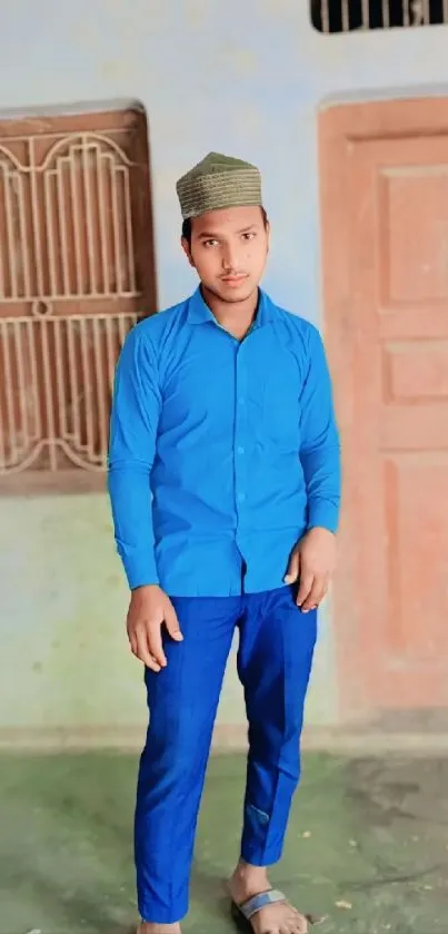 Man in blue outfit standing indoors with vibrant background.