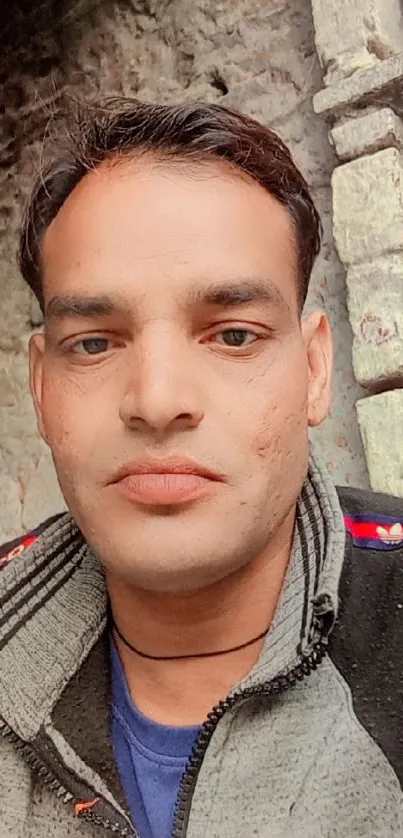 Close-up portrait of man in casual attire with a natural stone background.