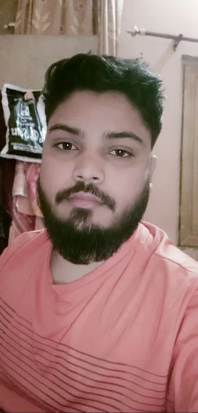 Young man in coral shirt, casual pose.