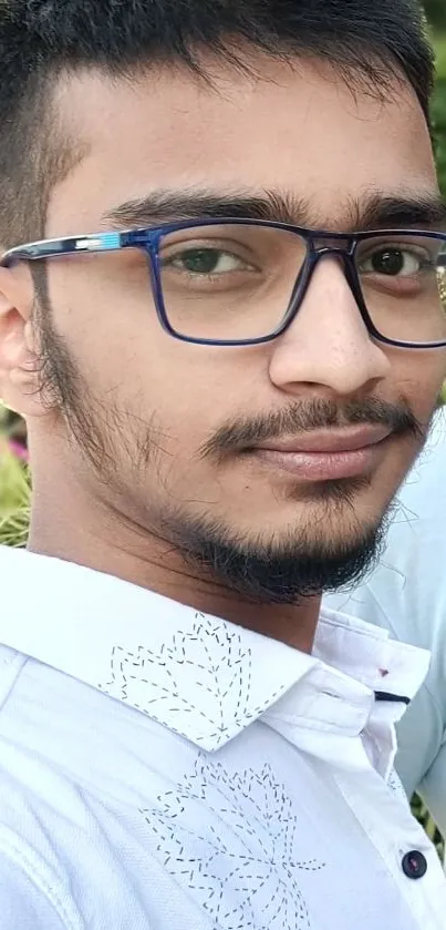 Portrait of a young person with blue glasses in a white shirt.