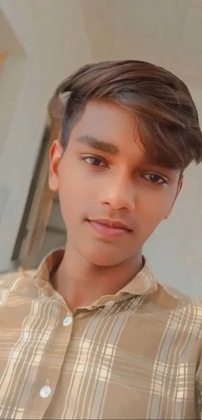 Portrait of a young man in a beige striped shirt, softly lit.