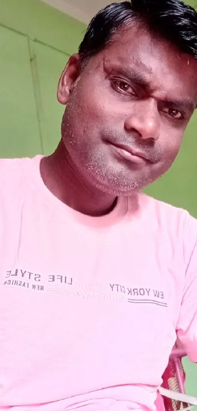 Portrait with pink shirt against light green wall.