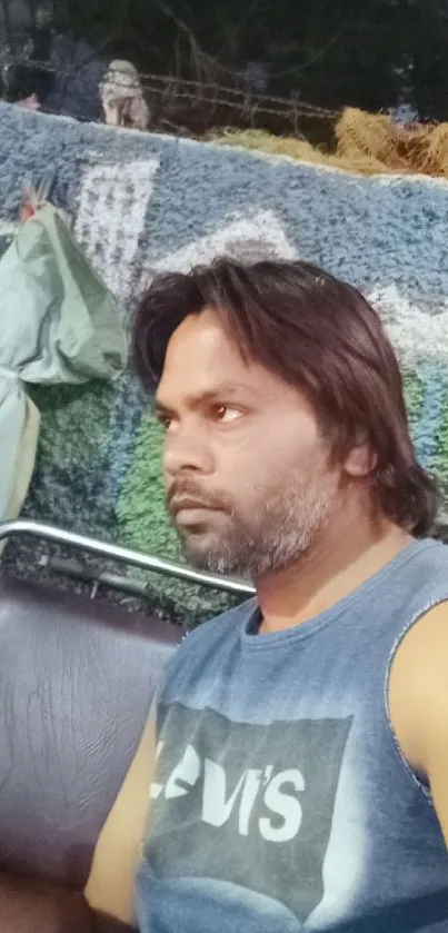 Portrait of a relaxed man in a casual indoor setting, wearing a sleeveless shirt.