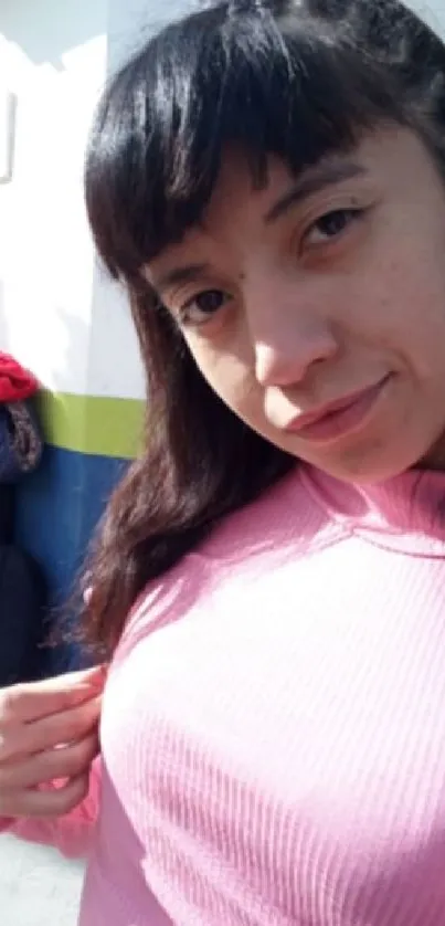 Young woman in pink sweater posing outdoors.