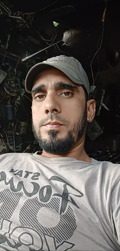 Portrait of a man wearing a cap in natural light, set against a dark background.