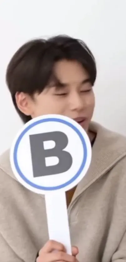 Casual portrait of a person holding a large letter sign in minimalistic setting.