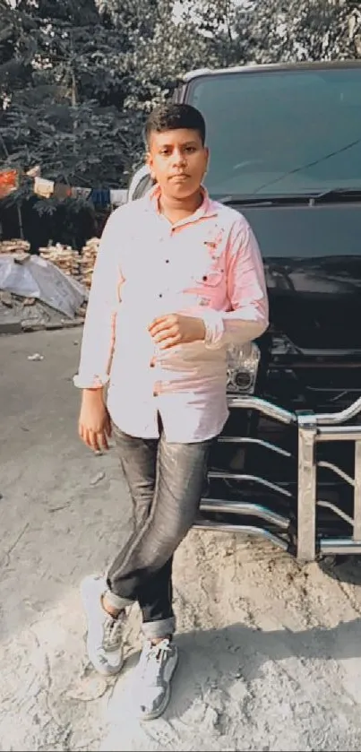 Young man posing by a black vehicle outdoors.