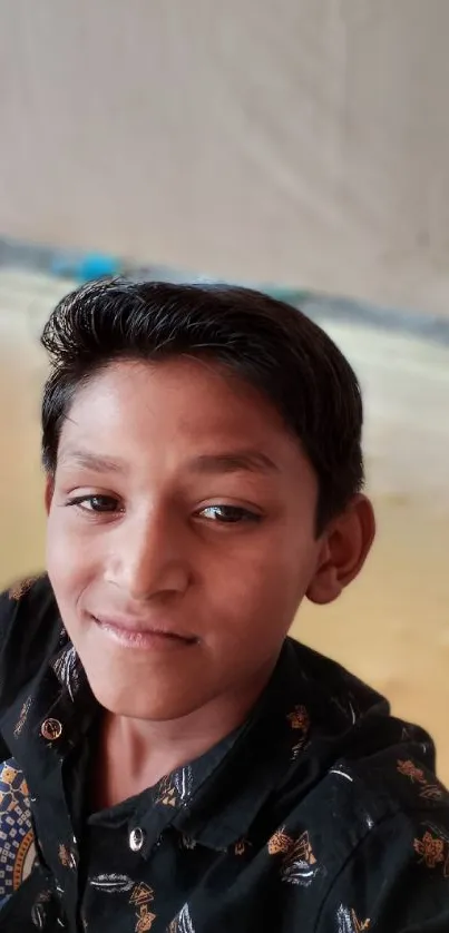 Young boy smiling in a casual portrait setting with warm, beige tones.