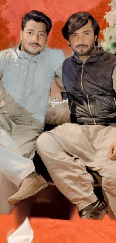 Two friends sitting casually with a terracotta background and colorful accents.