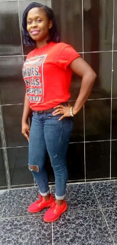 Woman in red shirt and jeans against tiled wall.