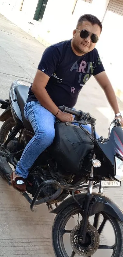 Man in casual attire on a black motorcycle.