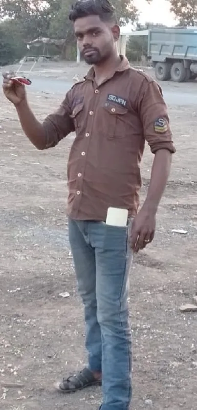 Person standing on the roadside with brown shirt in rural area.