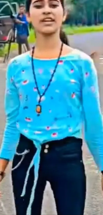 Girl in blue top walking along a road.