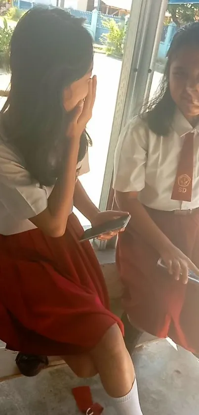 Two students in uniform chatting casually on a school day.