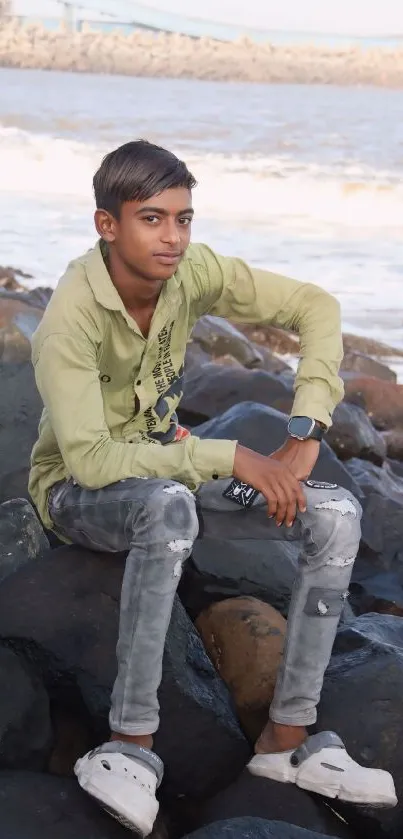 Young person sitting on seaside rocks with ocean view.