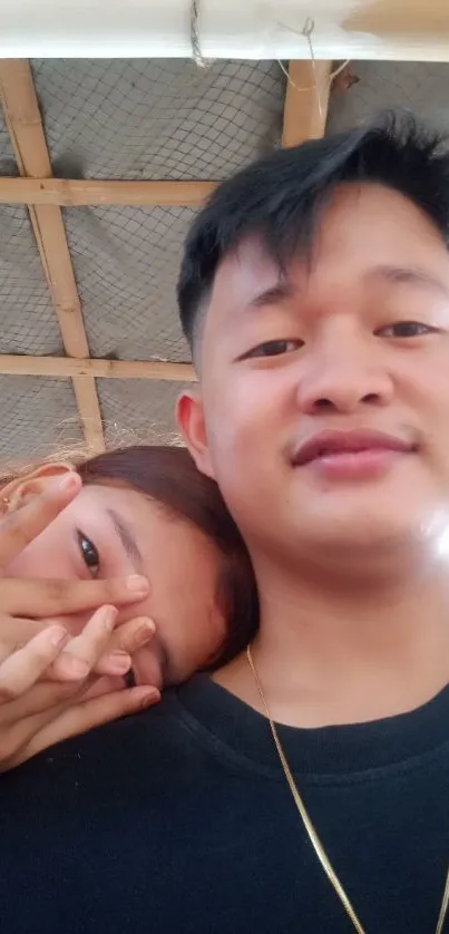 Casual selfie of two people under a wooden roof.