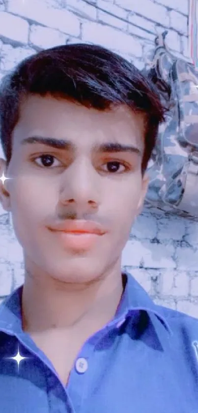 Young person in blue shirt with brick wall backdrop.