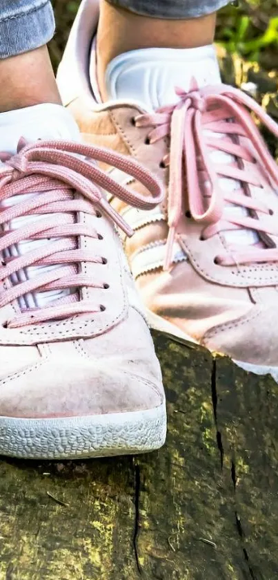 Pink sneakers on rustic wood surface.