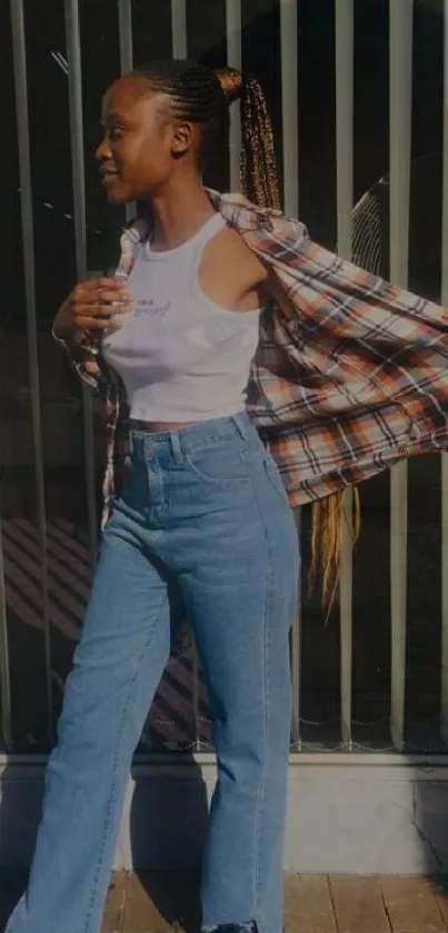 Woman in denim jeans and plaid shirt posing in sunlight.