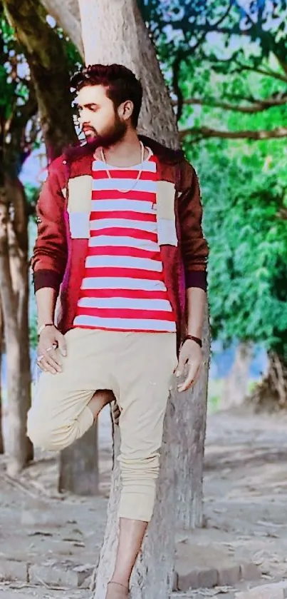 Person in red striped shirt stands among trees.