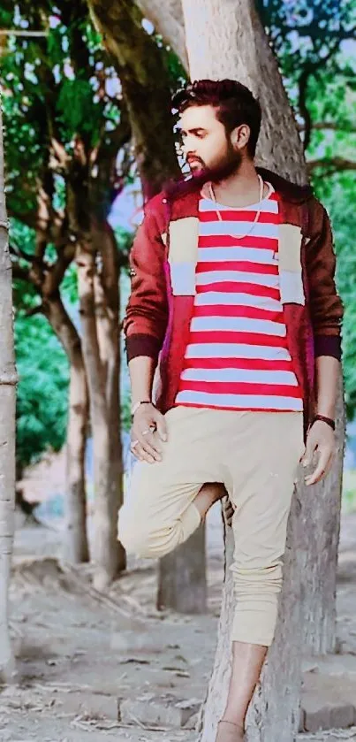 Man in striped shirt relaxes by trees in an urban nature setting.