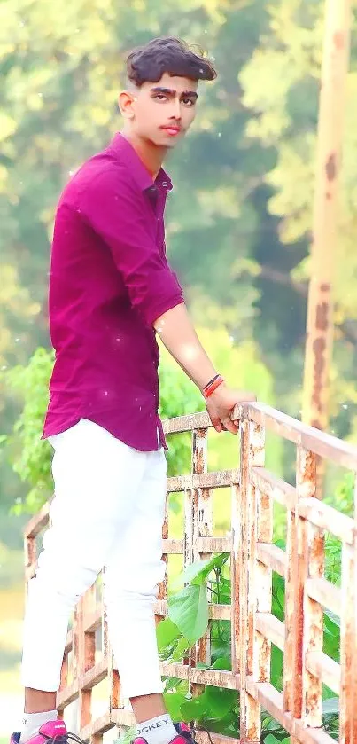 Man in burgundy shirt and white pants by green backdrop.