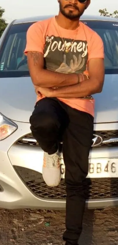 Man in vibrant t-shirt leaning on car, casual outdoor style.