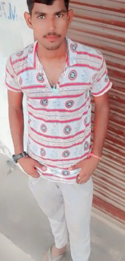 Young man in stylish patterned shirt against a rustic background.