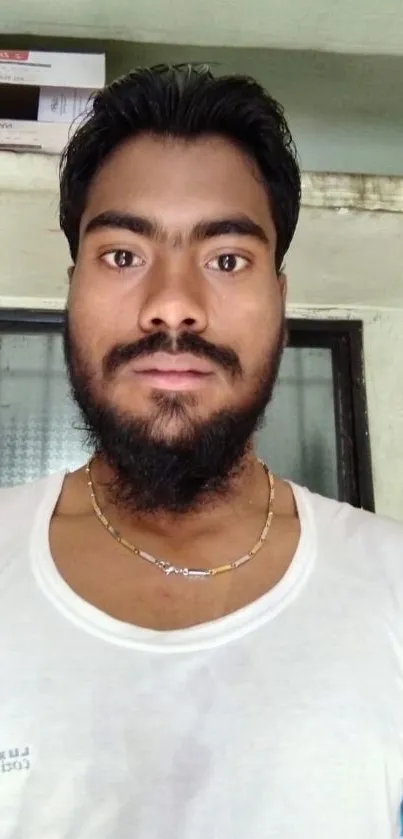 Casual portrait of a bearded man indoors wearing a white shirt.