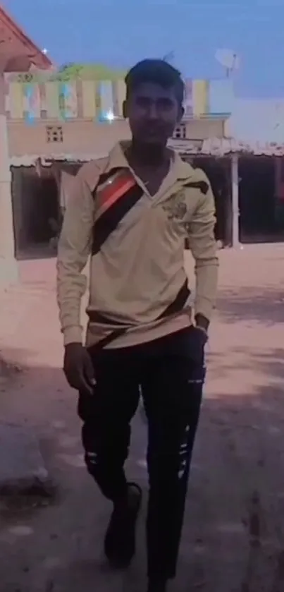 Young man in casual attire walking outdoors under clear sky.