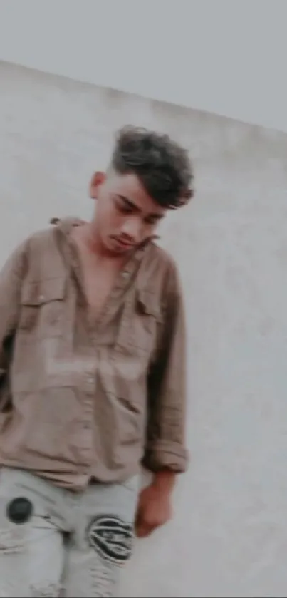 Young man in casual clothes leaning against a wall.