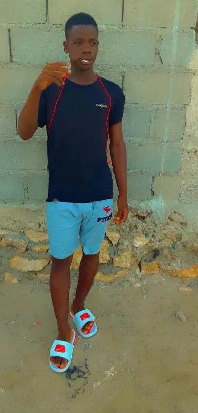 Young man in casual attire against a stone wall background.