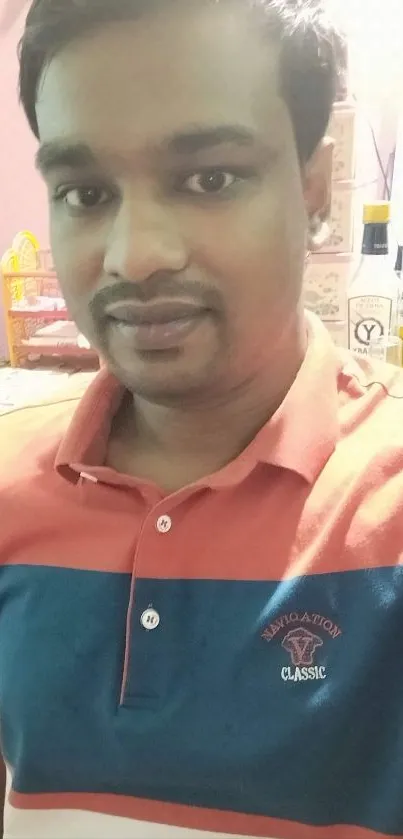 Man in orange and blue shirt in a colorful room.