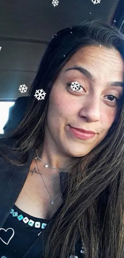 Woman takes a selfie in a car with a casual smile, long hair flowing.