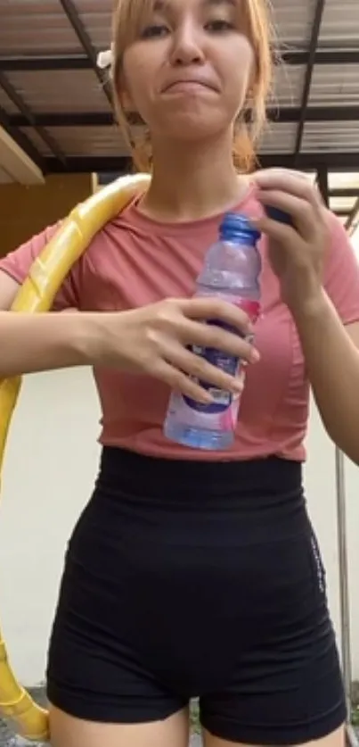 Young woman in workout attire holding water bottle.