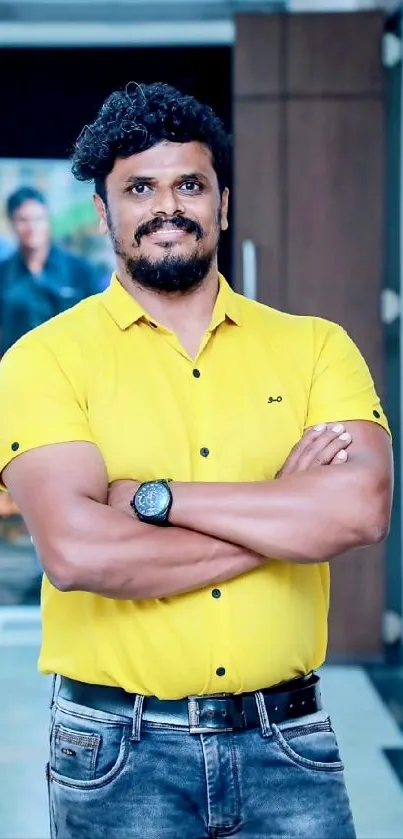 Man in a bright yellow shirt standing confidently indoors.