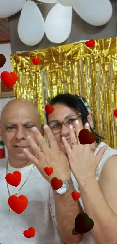 Couple celebrating with hearts and gold decor.