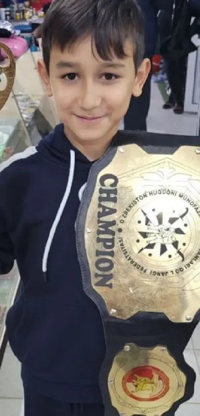 Young boy holding a large trophy and championship belt.