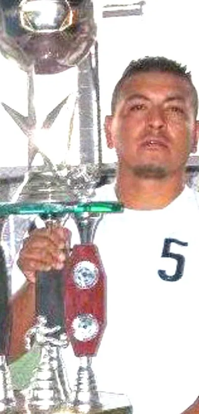 Soccer player proudly holds a shiny silver trophy.