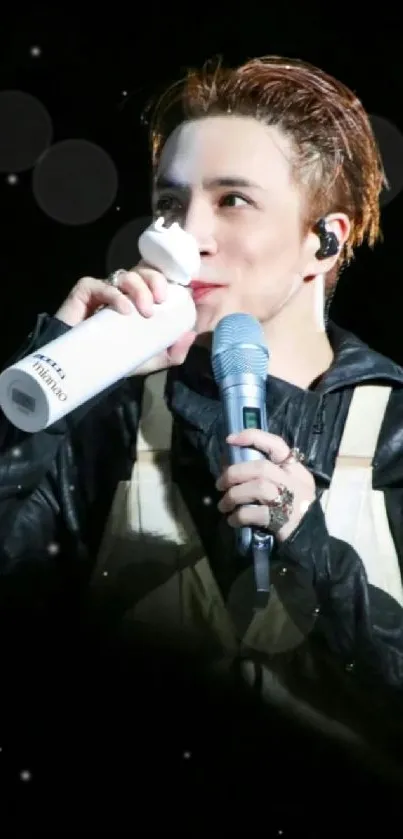 Performer on stage with microphone and bottle.