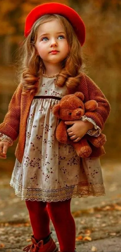 Little girl in autumn attire holding a teddy bear.