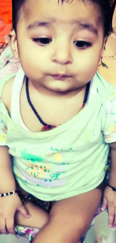 Adorable baby in casual attire sitting on bed.