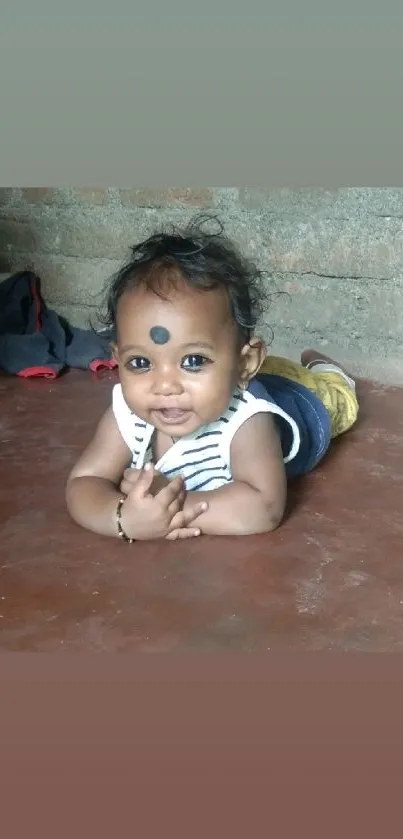 Adorable baby lying on floor with charming smile, in striped outfit.