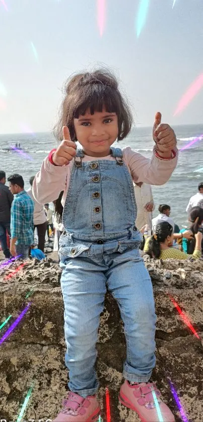 Happy child on beach wall with ocean backdrop.