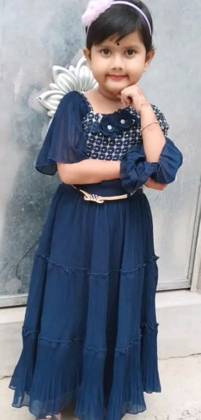 Young girl in a stylish navy blue dress, standing confidently.