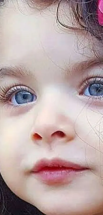 Toddler with blue eyes and curly hair, adorned with a pink flower, mobile wallpaper.