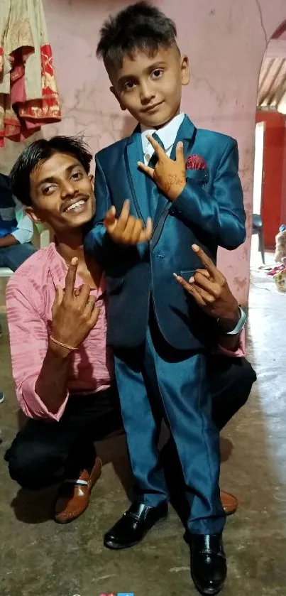 Child and adult posing in a colorful indoor setting, highlighting blue suit.